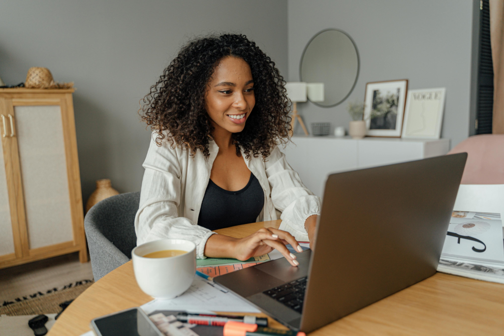 black woman working at desk on laptop looking happy 